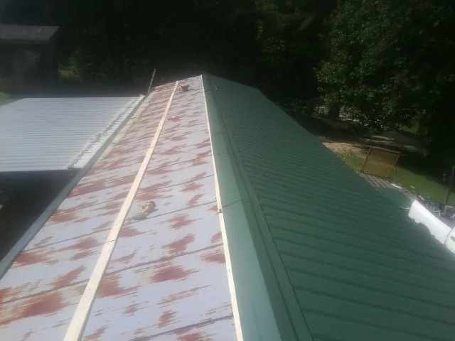 Old rusted panels beside newly installed green metal roofing — Wind Damage Roof Repair by Roofing Brothers in Otis