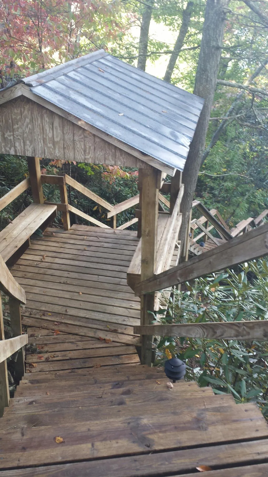 Metal roofed shelter over wooden steps on a wooded walkway — Skylight Repair & Installation work by our crew in Otis